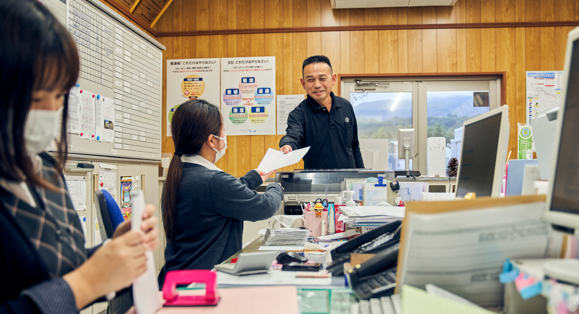 事務員の女性に書類を渡す男性